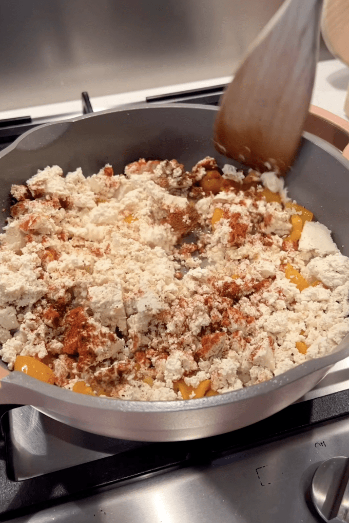 Vegetables, crumbled tofu, and spices in a large pan.