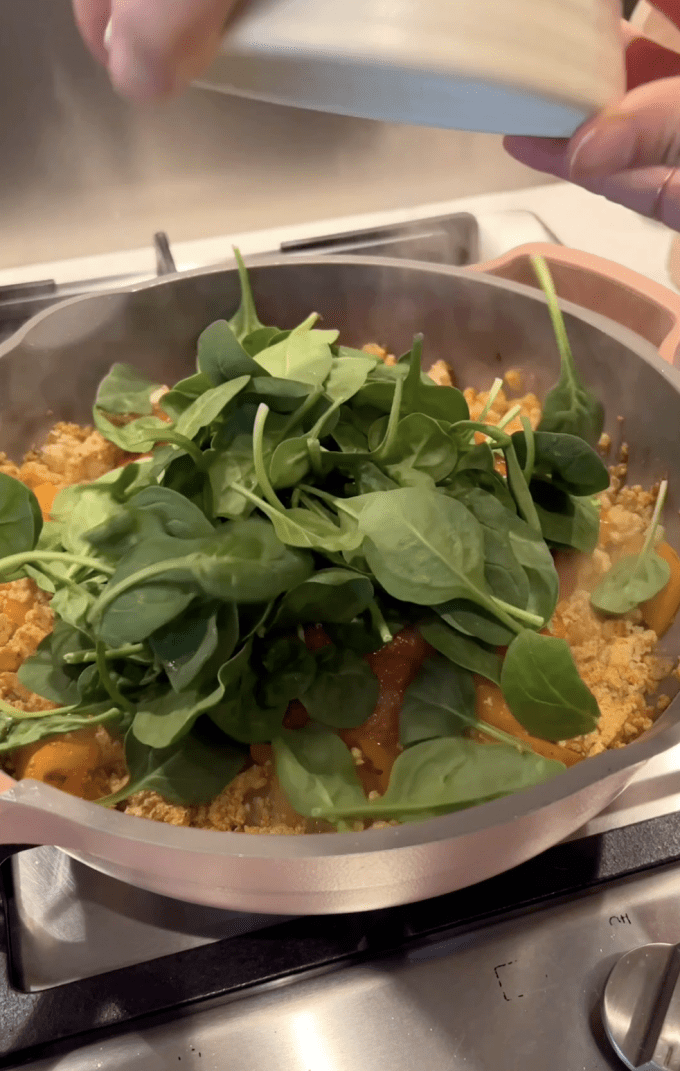 Spinach being added to tofu-vegetable mixture.
