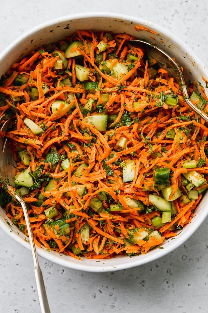 Cucumber shredded carrot and celery salad in a large white bowl.
