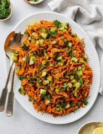 Cucumber carrot celery salad with herbs on a large white serving plate.