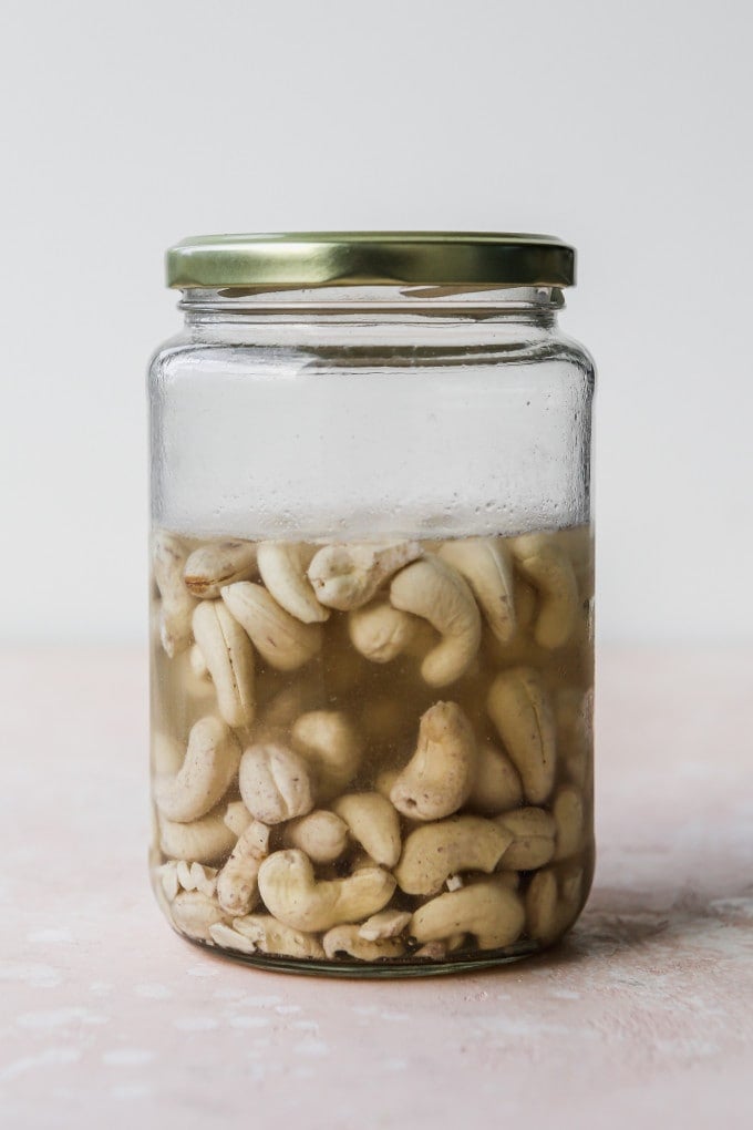 Cashews soaking in a glass jar with lid.