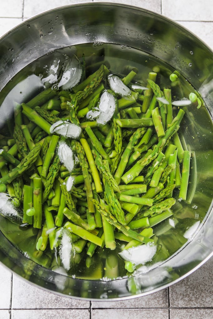 Blanched asparagus and peas in an ice bath.