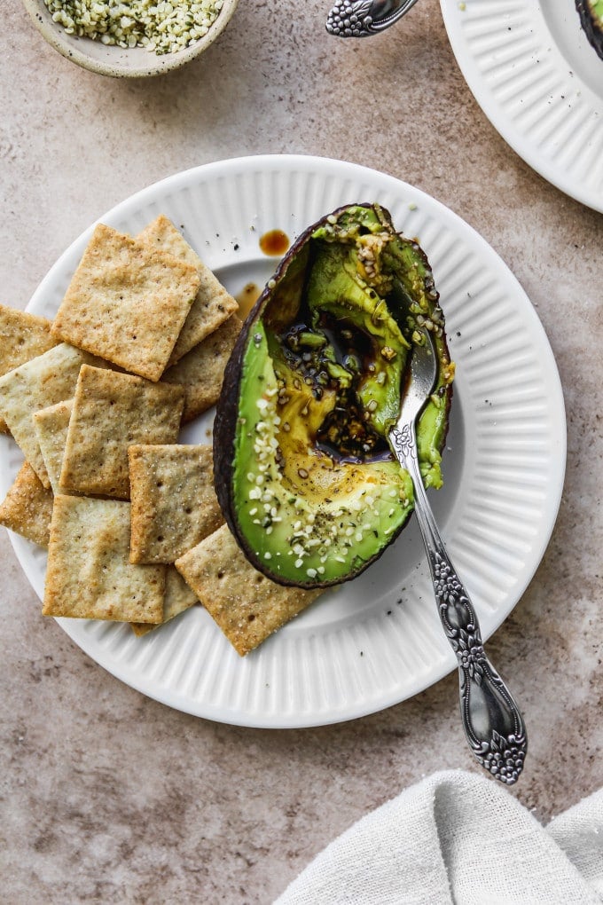 Half an avocado filled with balsamic vinegar and served with crackers as a snack.