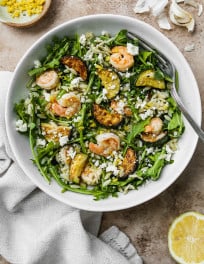 Orzo salad with shrimp in a white bowl.