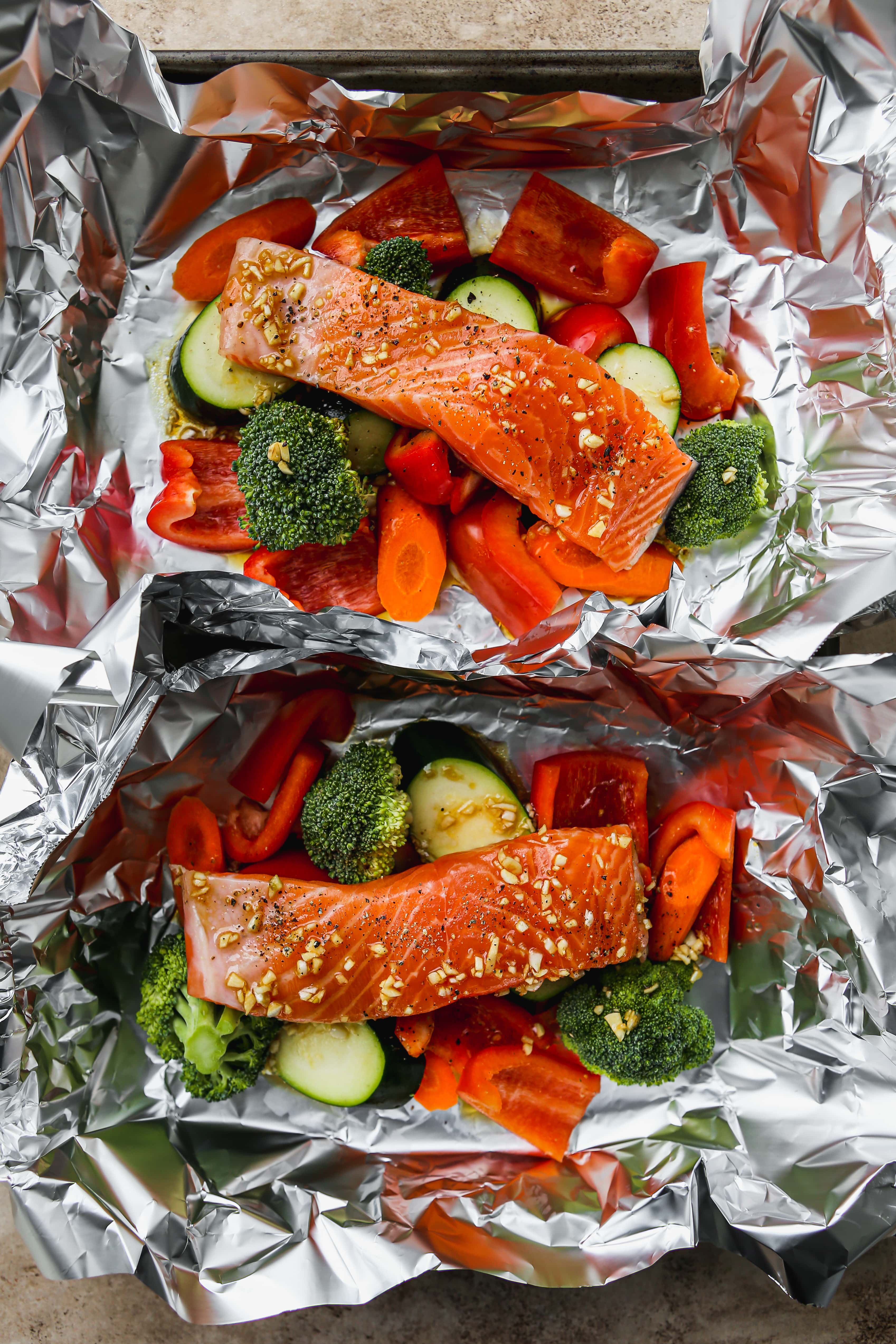 Uncooked salmon on top of vegetables in foil.