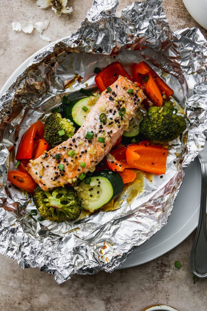 Baked salmon over veggies in a foil parcel.