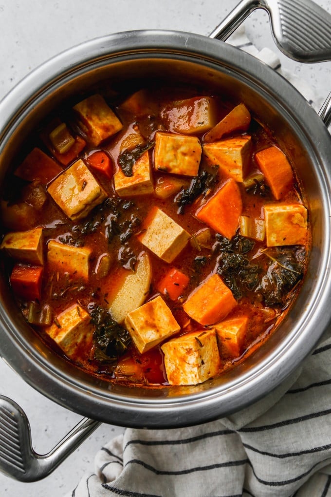 Vegetable stew with potatoes, root vegetables, and tofu in a large pot.