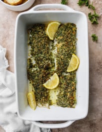 Herb crusted cod in a white baking dish.