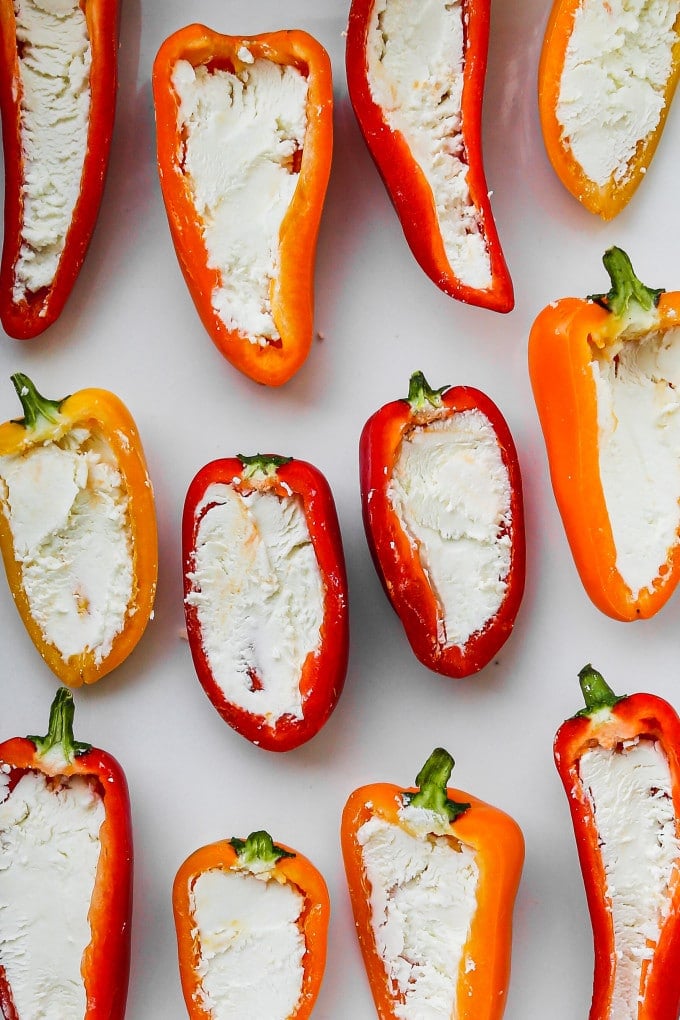 Halved mini peppers with goat cheese inside their centers.