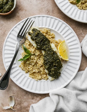 Baked pesto cod on a plate of quinoa.