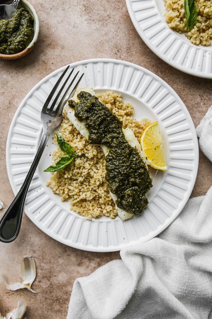 Baked pesto cod on a plate of quinoa.