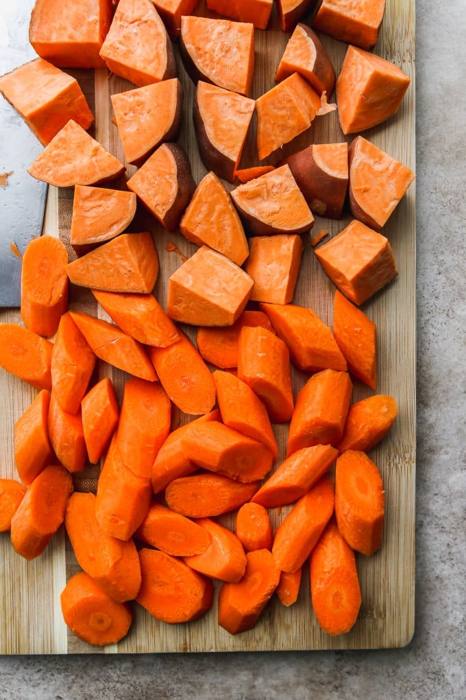 Chopped sweet potatoes and carrots on a cutting board.