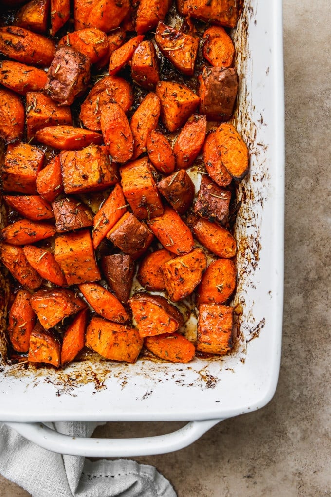 Roasted sweet potatoes and carrots in a baking dish.