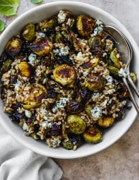 Roasted brussels sprout salad with farro, dried cranberries, and blue cheese in a white bowl.