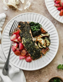 A serving of baked chimichurri salmon with a side of vegetables.