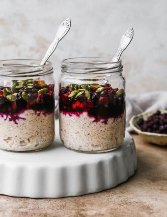 Overnight oats with frozen fruits in two glass jars.
