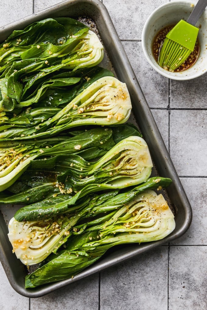 Bok choy slices on a baking dish brushed with sauce.