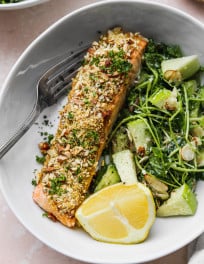 Almond crusted salmon plated with lemon and a side salad.