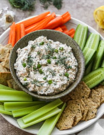 Canned salmon dip on a large platter with crackers and vegetables.