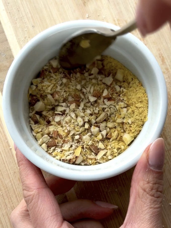 Chopped almonds and nutritional yeast stirred together in a bowl.