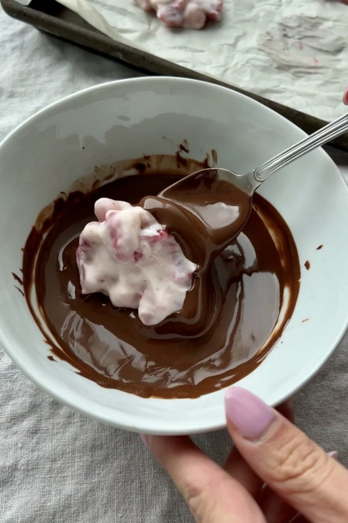 Dipping strawberry yogurt clusters into melted chocolate.