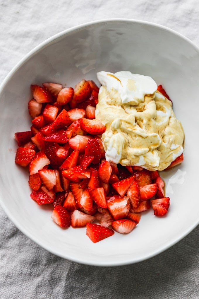 Diced strawberries with greek yogurt and vanilla extract in a bowl.
