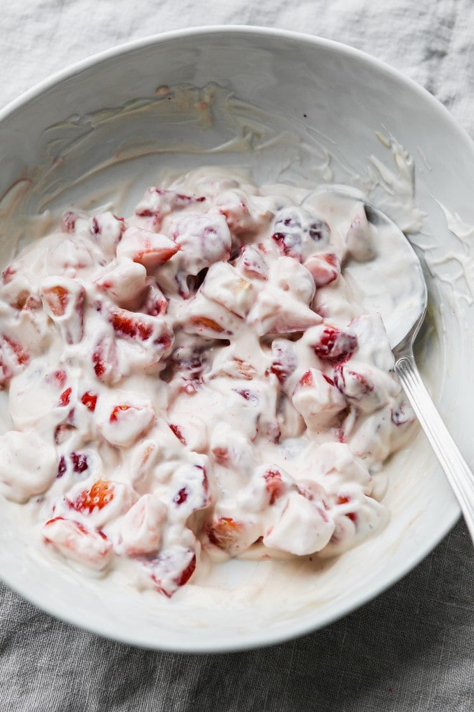 Diced strawberries tossed in greek yogurt in a bowl.