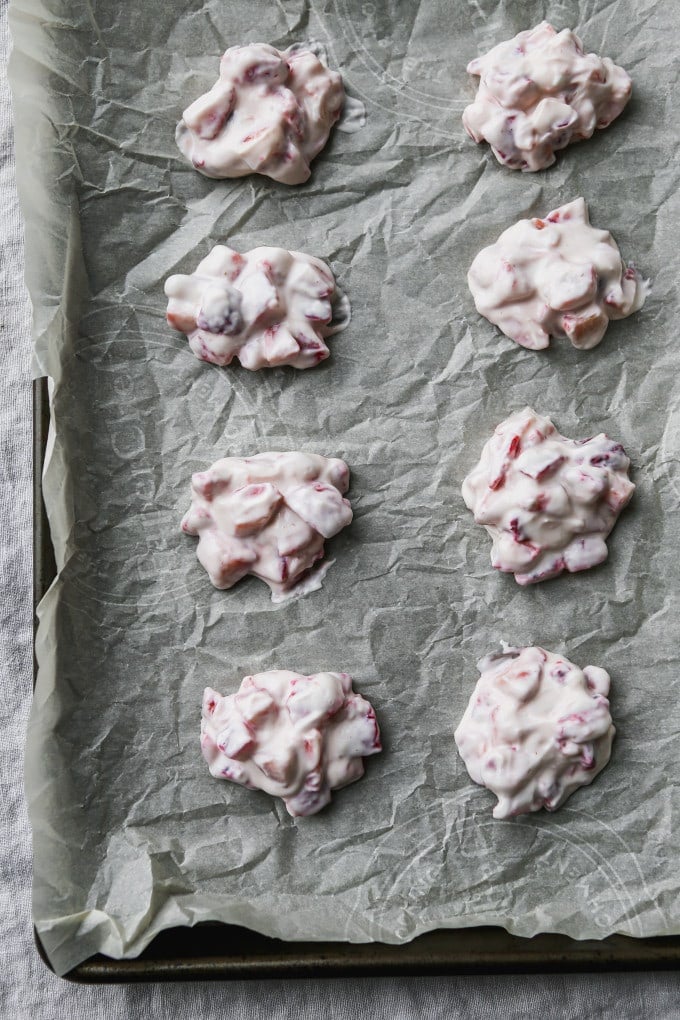 Strawberry yogurt clusters on a parchment-lined baking sheet.