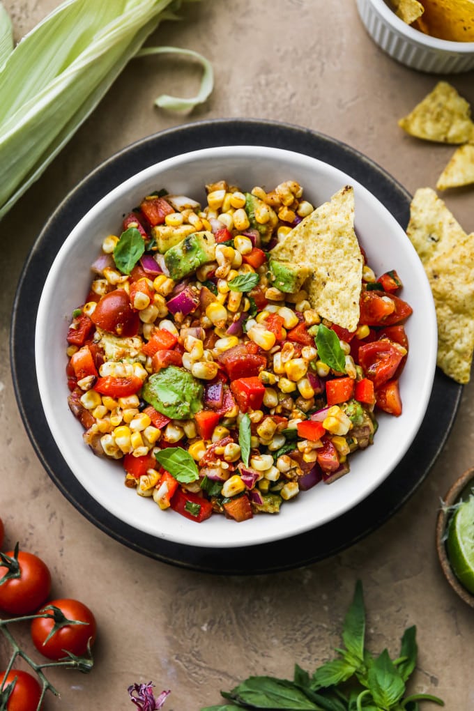Roasted corn salsa served in a bowl with tortilla chips.