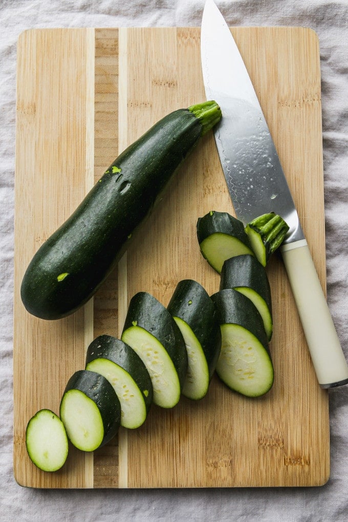 Zucchini being sliced into rounds.