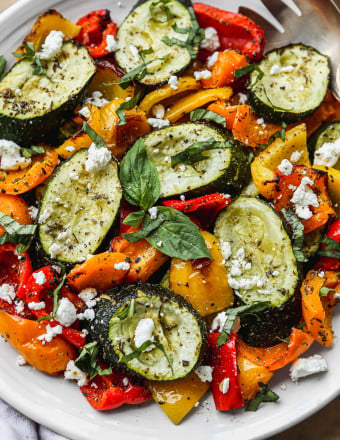 Roasted peppers and zucchini on a white serving platter.