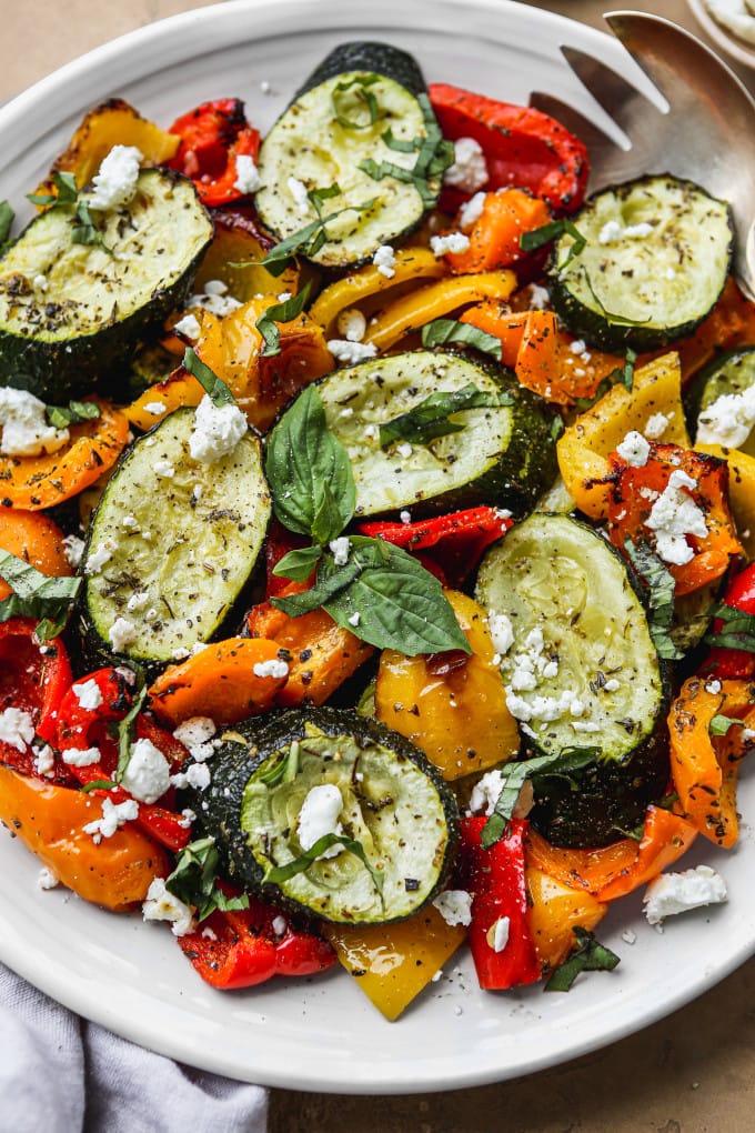 Roasted peppers and zucchini on a white serving platter.