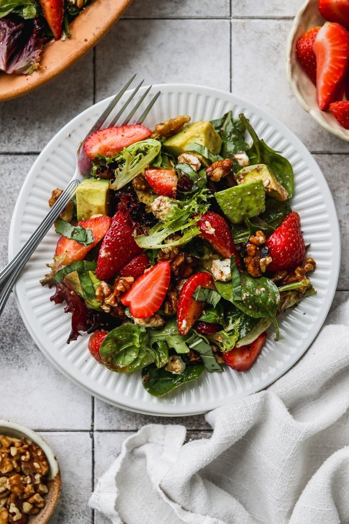 Strawberry salad with walnuts, goat cheese, basil, and avocado tossed in balsamic dressing.