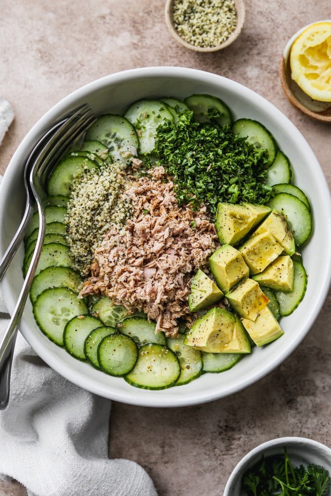 Cucumber tuna salad with avocado, parsley. and hemp seeds in a bowl.