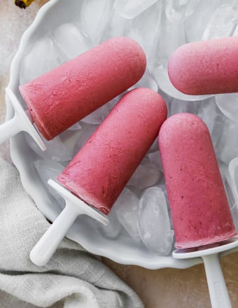 Strawberry banana yogurt popsicles displayed on a bowl of ice.
