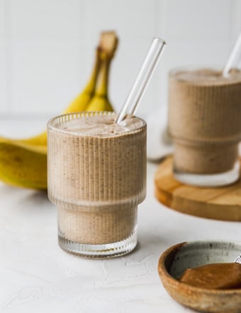 Banana almond butter smoothie poured into two glasses.