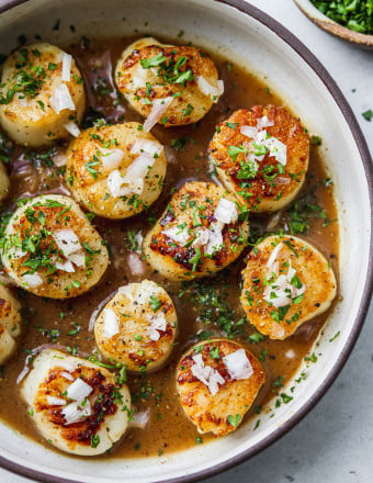 Pan-seared scallops in a bowl with vinegar, shallots, and parsley.