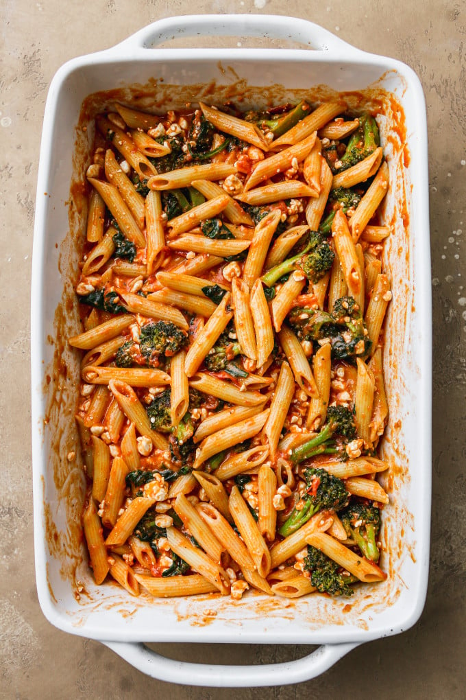 Cooked pasta, tomato sauce, cottage cheese, and veggies stirred together in a large baking dish.