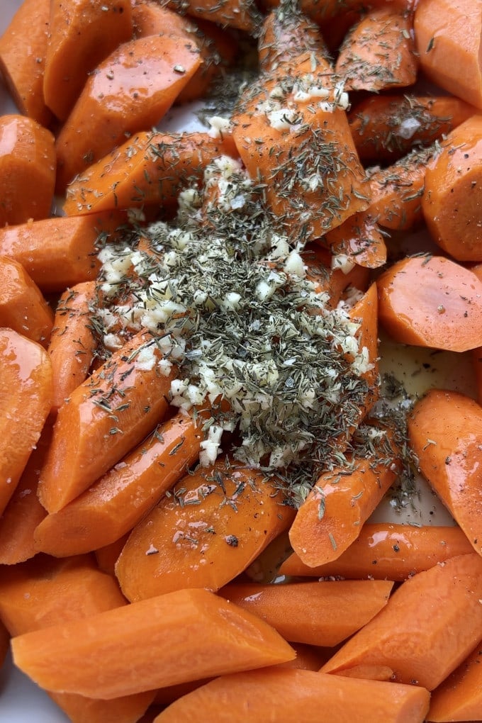 Carrots with seasonings added to them in baking dish.