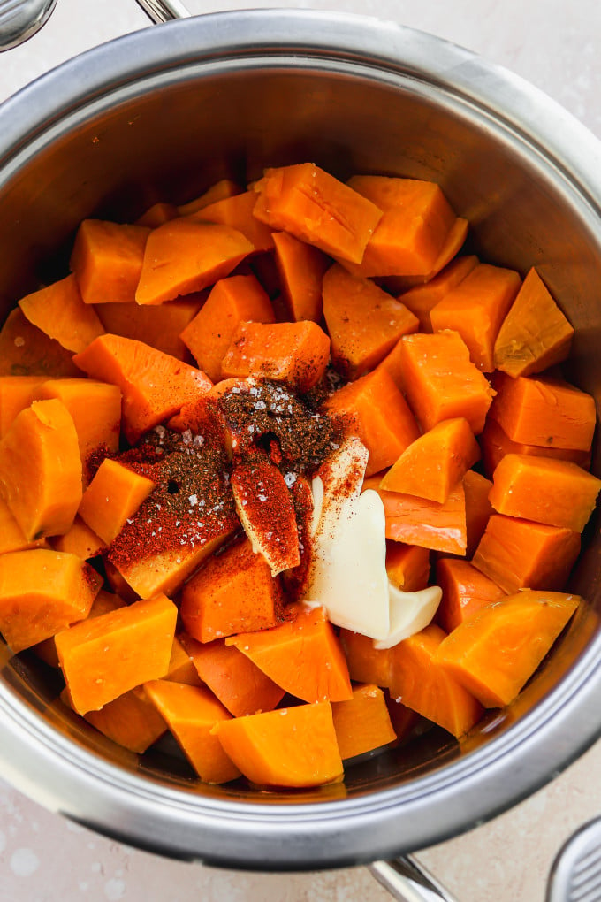 Cooked sweet potato chunks in a pot with seasonings added.