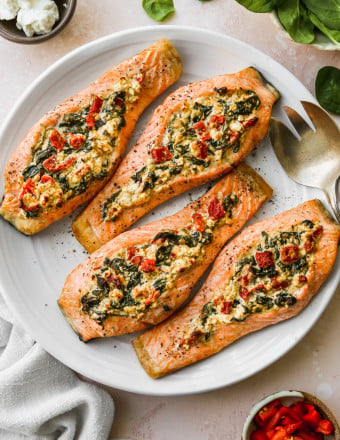 Spinach and feta stuffed salmon fillets on a white serving plate.