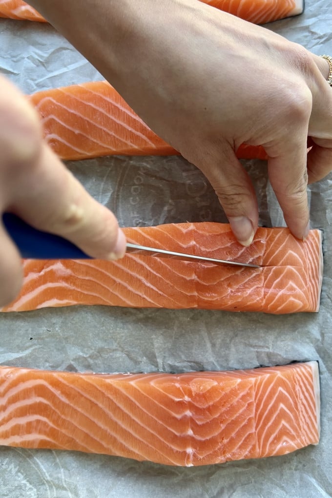 Cutting salmon fillets down the center using a sharp knife.