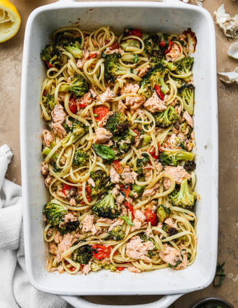 Cooked pasta stirred into baked salmon and veggies, in baking dish.